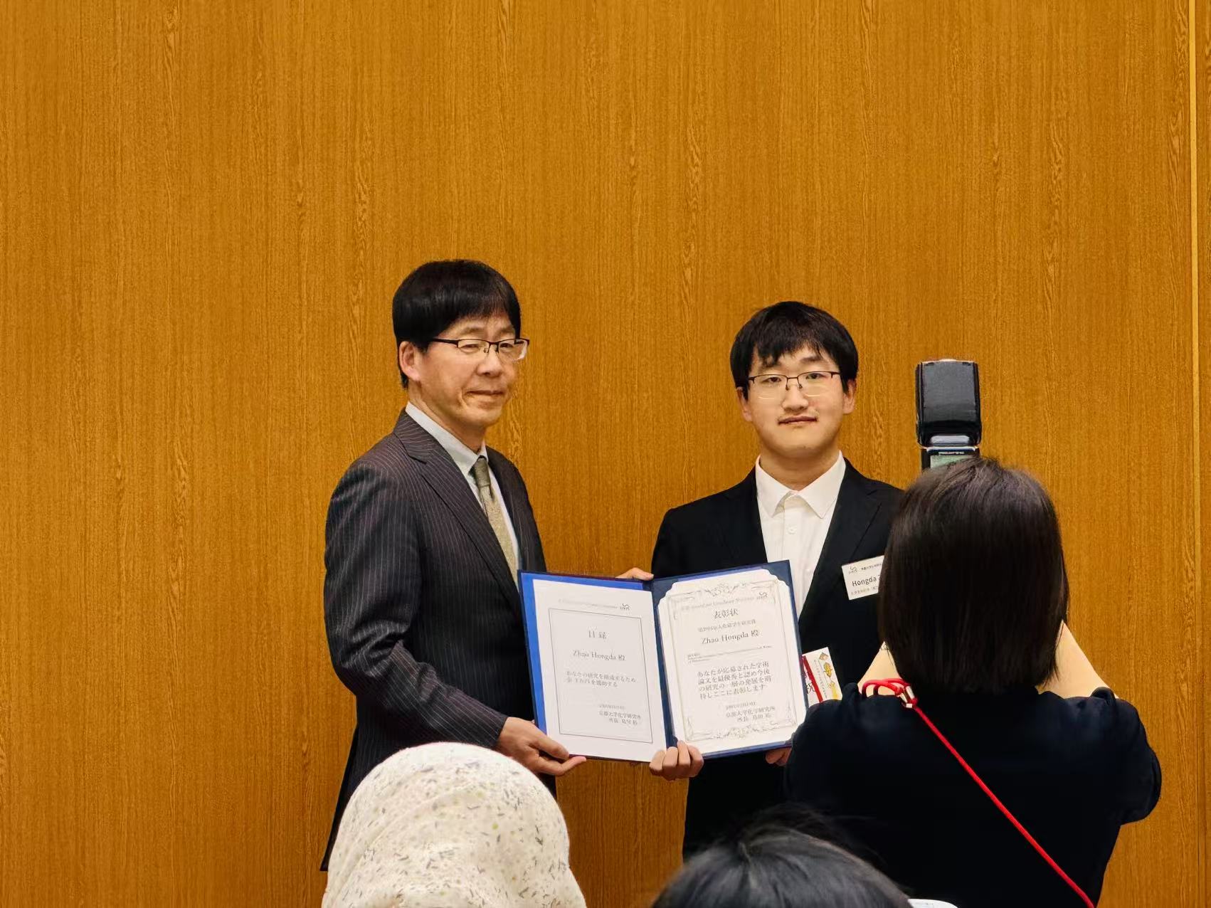 Hongda Zhao and an award presenter display the open ICR Award certificate during the ceremony.
